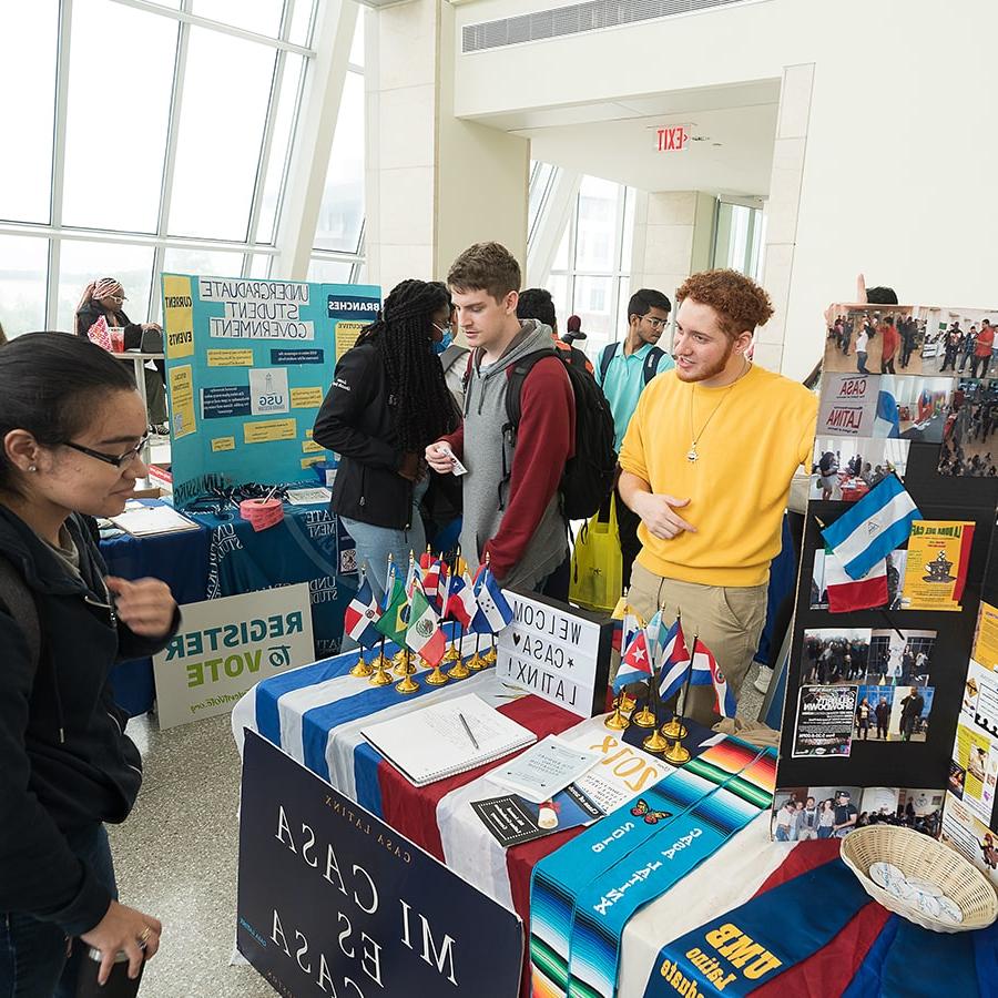 Student tables for club with banner reading mi casa es su casa and flags from Spanish speaking countries.